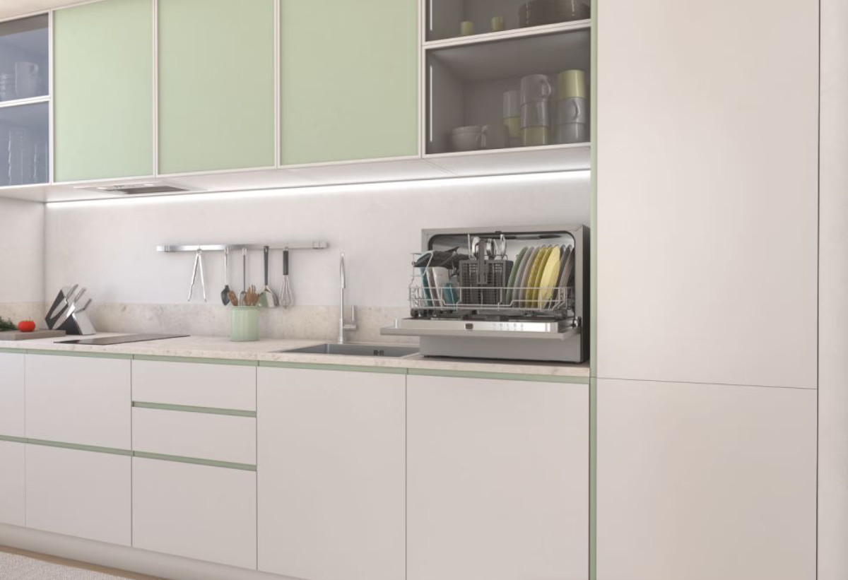  Στην εικόνα απεικονίζεται το πλυντήριο πιάτων τοποθετημένο στον πάγκο μιας κουζίνας με ανοιχτή πόρτα και γεμάτο με σκεύη.